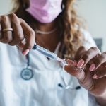 Profissional de saúde prepara uma seringa com vacina em ambiente clínico.