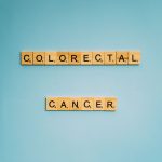 Peças de jogo de palavras formam a expressão “Colorectal Cancer” sobre fundo azul-claro.