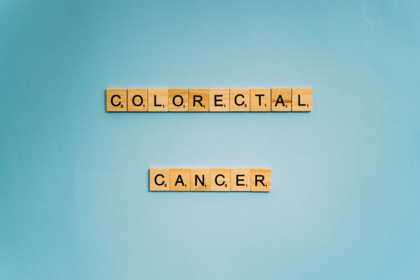 Peças de jogo de palavras formam a expressão “Colorectal Cancer” sobre fundo azul-claro.