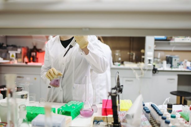 Cientista de jaleco e luvas manuseia amostras em um laboratório durante uma pesquisa.