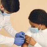 Profissional de saúde aplica uma vacina no braço de uma gestante em uma clínica.