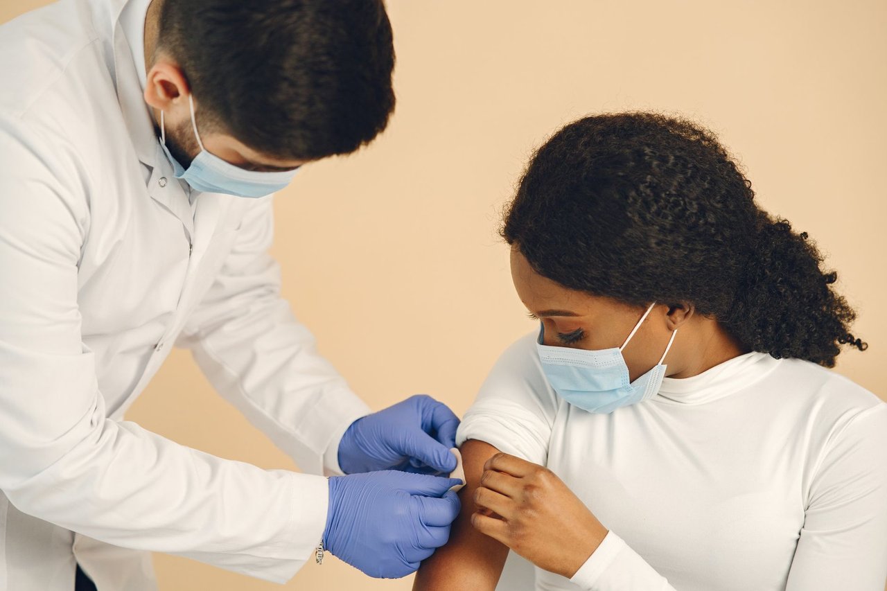 Profissional de saúde aplica uma vacina no braço de uma gestante em uma clínica.